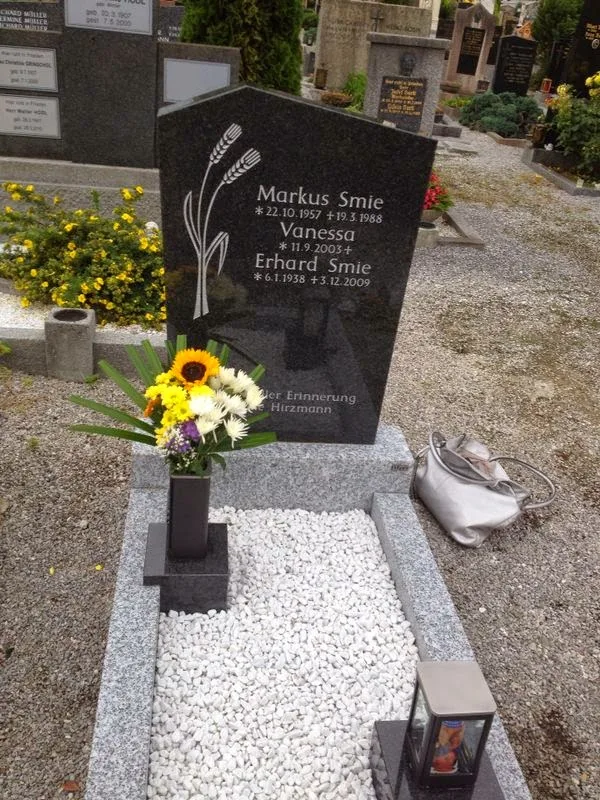 Schwarzer Grabstein mit Ährengravur und Kieseinfassung